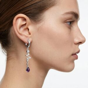 Profile view of a woman's ear wearing a silver hoop earring with a dangling chain and purple teardrop pendant